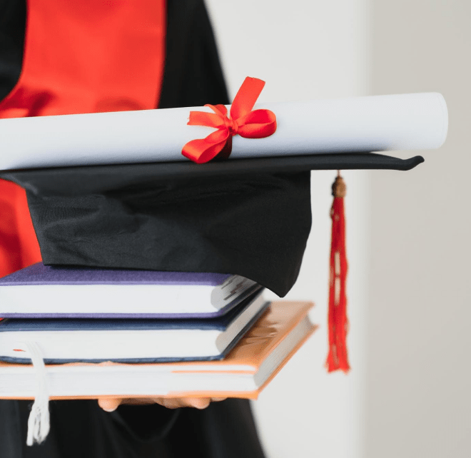 Студент у випускному одязі тримає книги та диплом 