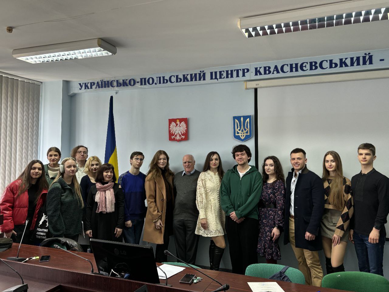 A group of people standing in front of a banner with the inscription ‘UKRAINIAN-POLISH CENTER KVASNEVSKY’ and the coats of arms of Ukraine and Poland. 